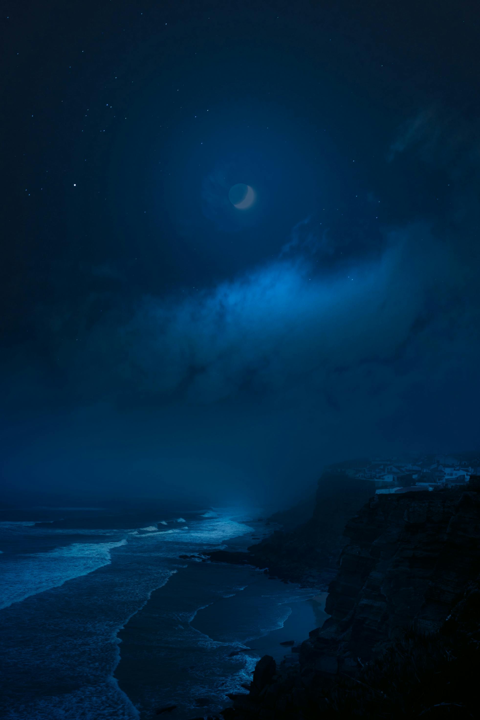 Ocean at night with a dim moon in the background